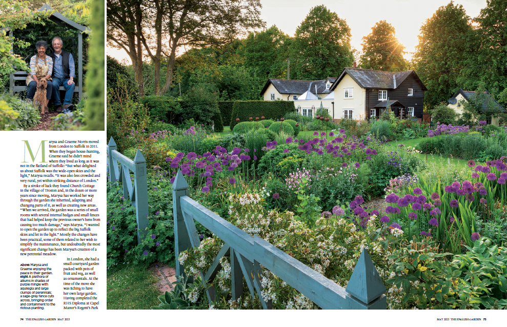 double page spread from the english garden showing beautiful country cottage garden with a riot of purple flowers and a white house in the background